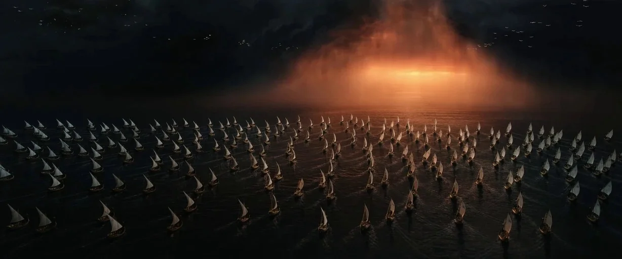 The Lord of the Rings: The Rings of Power (2022) movie still: establishing — A vast fleet of small sailing vessels navigates a dark, expansive open…