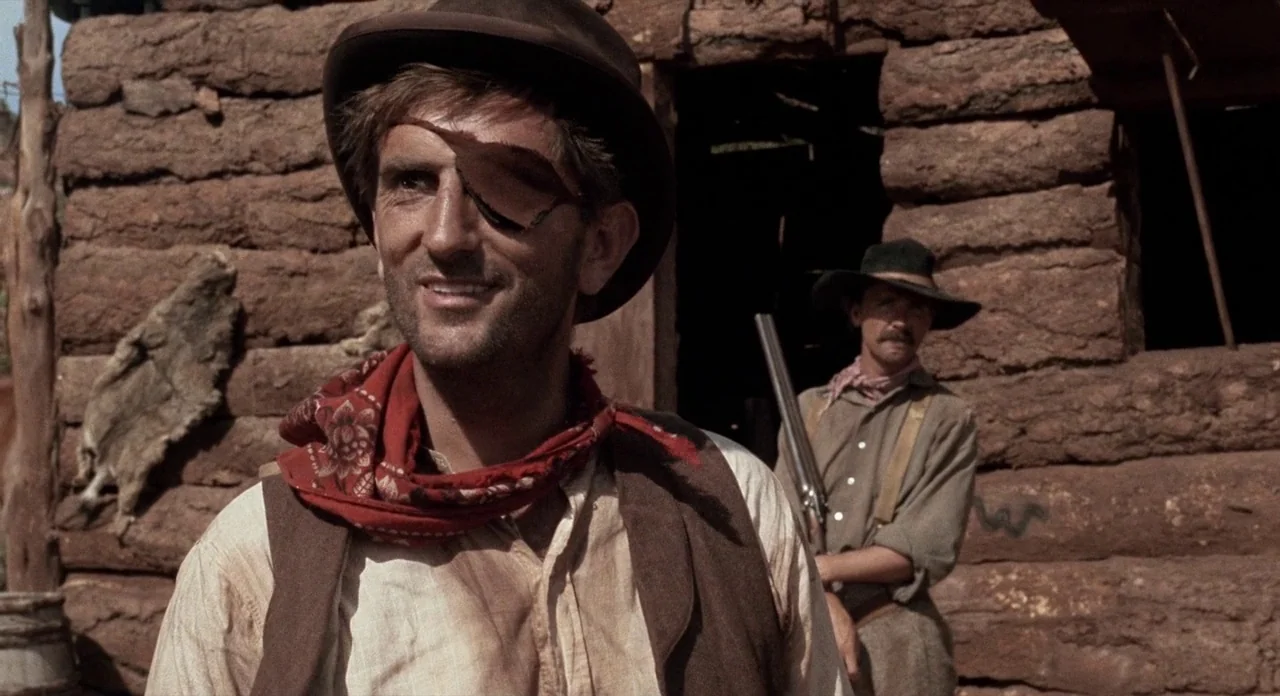 Ride In The Whirlwind (1966) movie still: medium — A rustic log cabin with horizontal timber logs and a small wooden doorway. A man with an eyepatch…