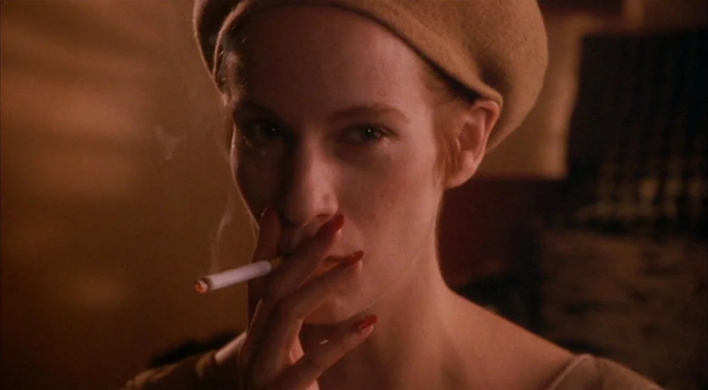 The Fisher King (1991) movie still: closeup — A dimly lit room with warm tones reflected on a woman's face. The woman wears a tan beret and holds a…