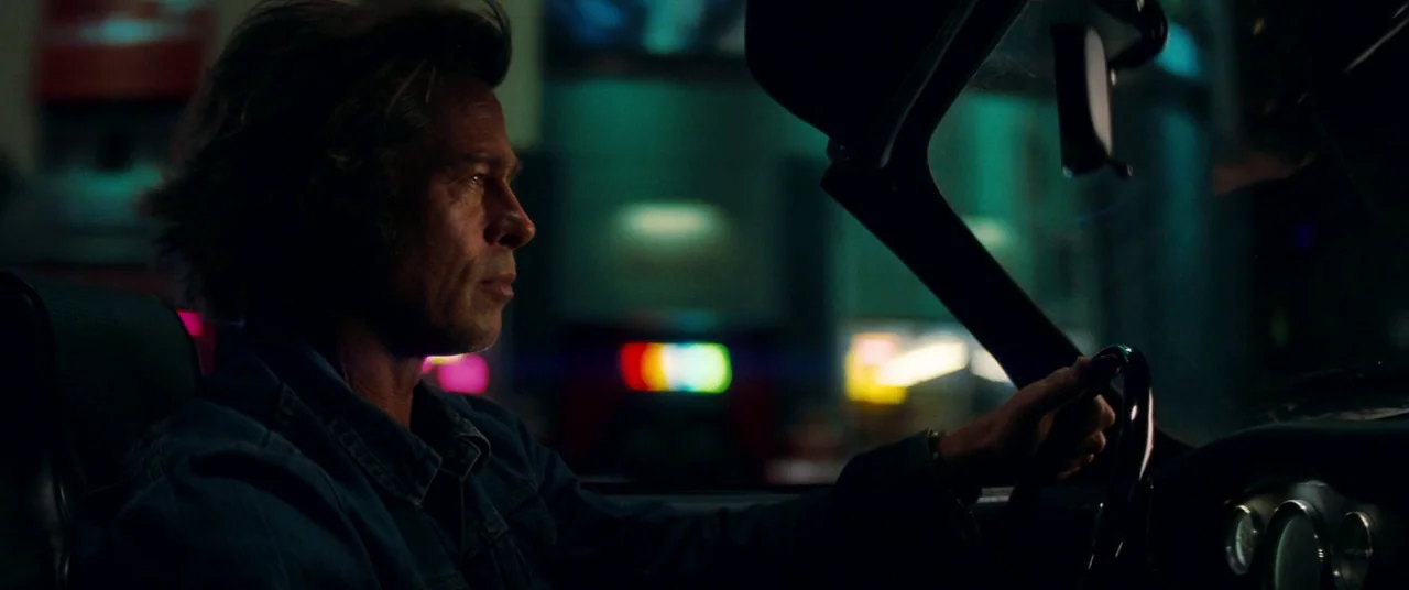 Once Upon a Time… In Hollywood (2019) movie still: medium — The interior of a moving car is dark with colorful reflections from neon city lights. A…