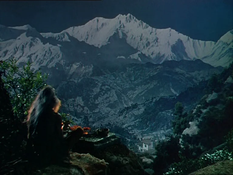 Black Narcissus (1947) movie still: wide — A dark mountainous landscape with a prominent snow-covered peak looms against a night sky. An elderly…