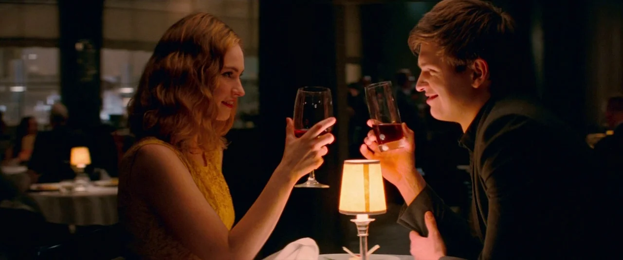 Baby Driver (2017) movie still: medium — A dimly lit restaurant interior features blurred patrons sitting at other circular tables. A man and woman…
