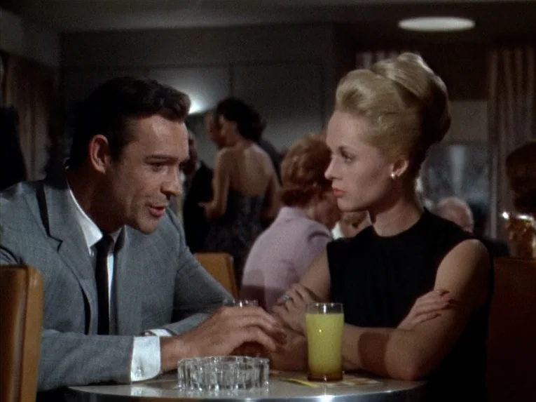 Marnie (1964) movie still: medium — A man and a woman sit at a small table inside a lounge area. They are facing each other while having a…