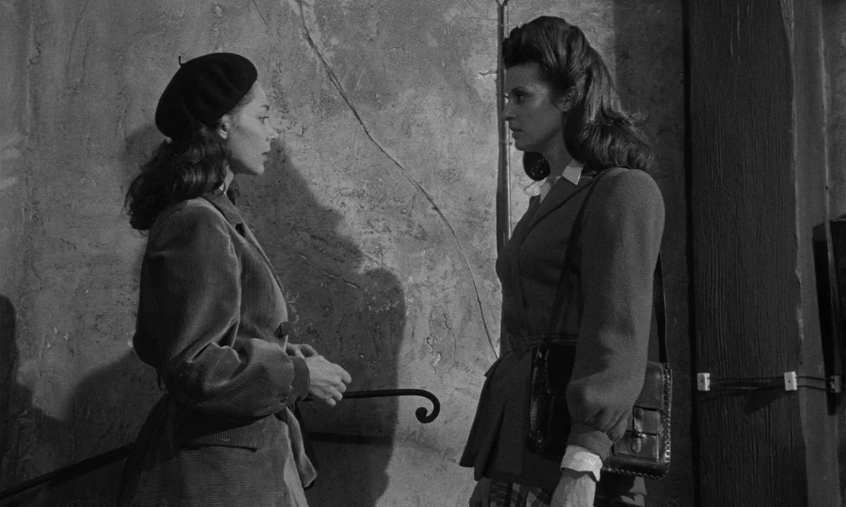 Léon Morin, Priest (1961) movie still: medium — A stone stairwell with rough plaster walls and a simple iron handrail. Two young women stand…