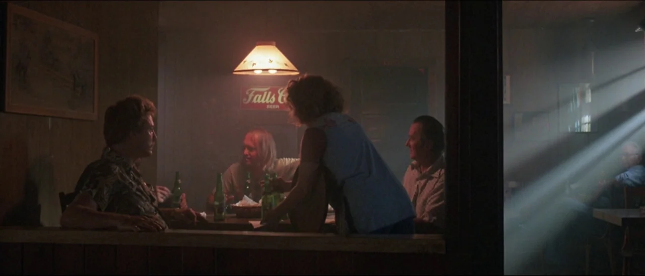 At Close Range (1986) movie still: wide — A dimly lit wooden tavern space is filled with smoke and warm ambient light. Several people sit around a…