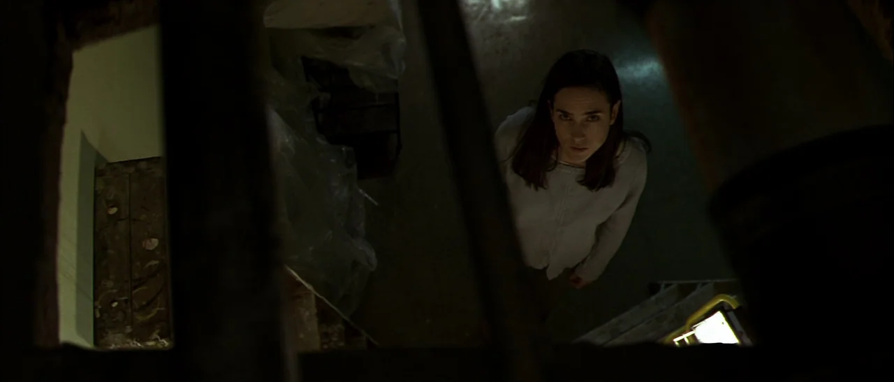 Dark Water (2005) movie still: medium — A dimly lit industrial basement space with dark corners and plastic-covered equipment. A young woman stands…