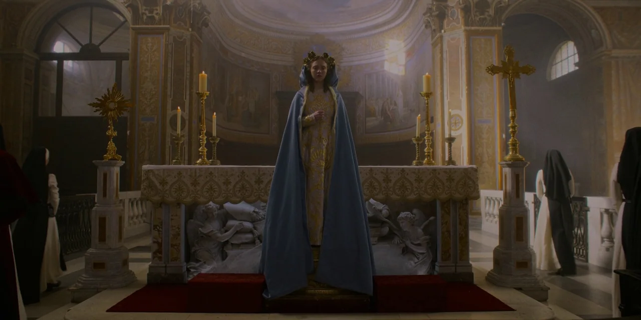 Immaculate (2024) movie still: fullbody — A stone altar inside an ornate church features religious sculptures and flickering candles. A young woman…