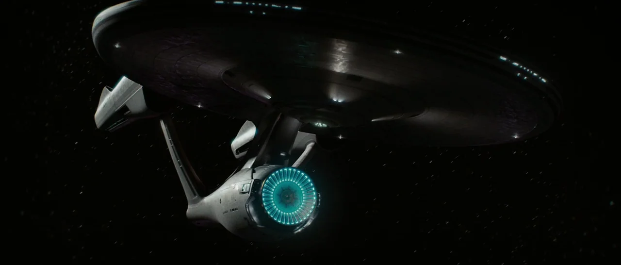 Star Trek (2009) movie still: wide — A large starship floats against a backdrop of distant, faint stars in deep space. The circular primary hull…