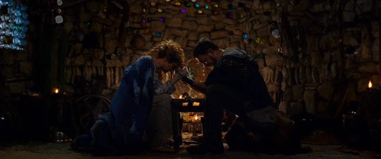 Cloud Atlas (2012) movie still: medium — A dark stone-walled dwelling is decorated with hanging colored crystals and various small items. A man and…