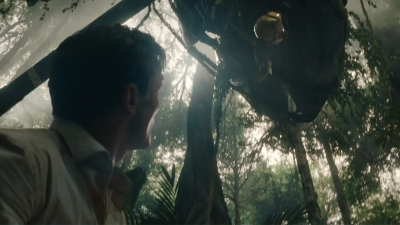 Jurassic World Rebirth (2025) movie still: medium — A dense forest environment with thick foliage and tall trees under bright daylight. A man stands…