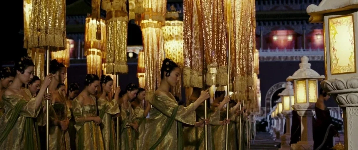 Curse of the Golden Flower (2006) movie still: wide — A night procession of women stands in a line within a walled courtyard. They hold tall poles…