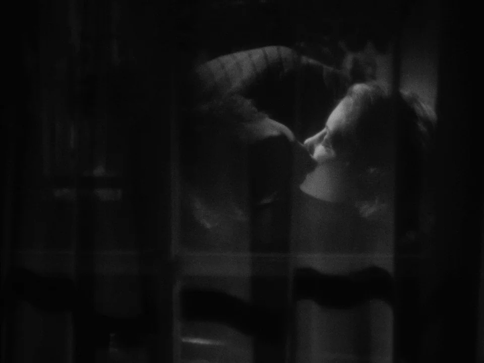 It Rains On Our Love (1946) movie still: closeup — Two individuals are positioned behind a dark, patterned curtain that obscures their faces. The…