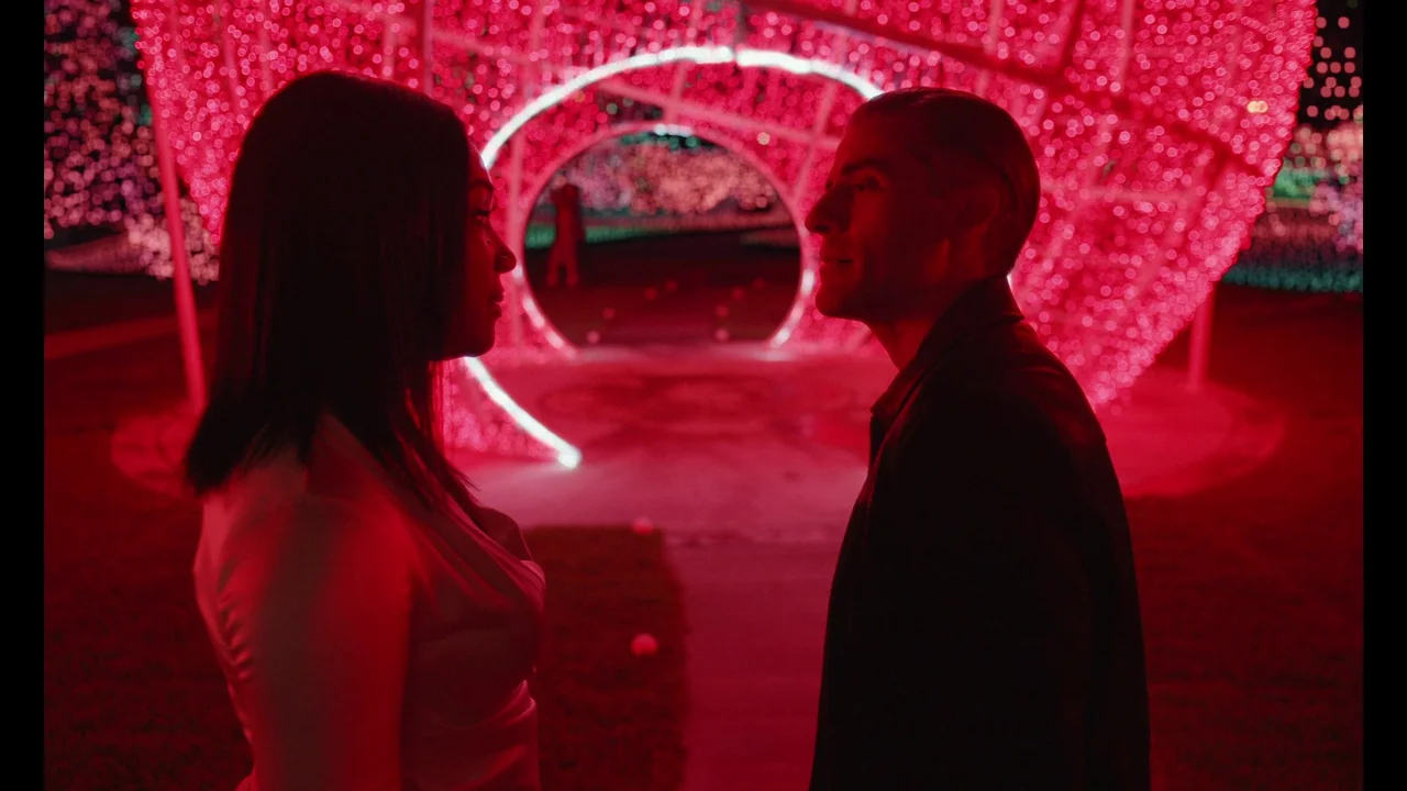 The Card Counter (2021) movie still: medium — A nighttime outdoor installation features a large archway made of dense pink LED lights. A man and…