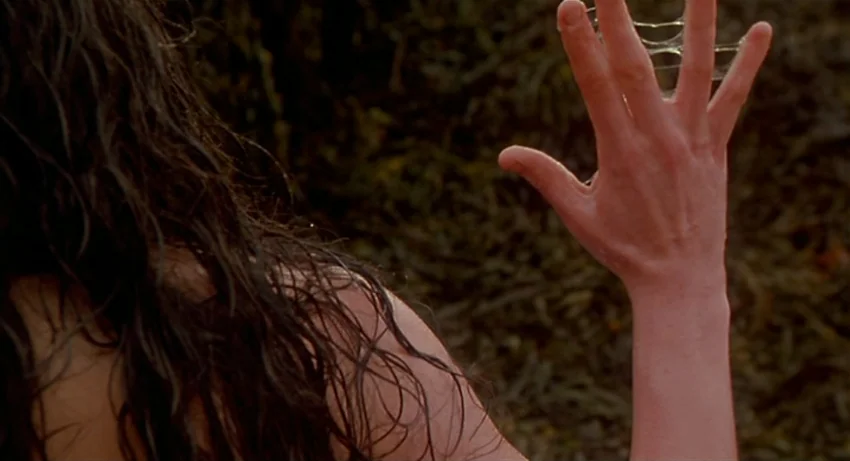 The Secret Of Roan Inish (1994) movie still: closeup — A wet, dark rocky terrain covered in seaweed provides the background environment. A woman…