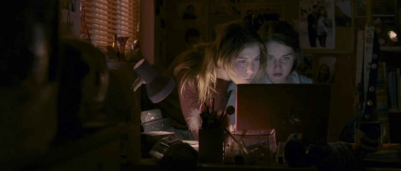 Tamara Drewe (2010) movie still: medium — Two teenage girls lean over an open laptop in a darkened room at night. Their faces are illuminated by the…