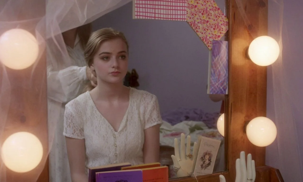 Ham on Rye (2019) movie still: medium — A girl sits in front of a mirror decorated with lights and colorful paper. Another person stands behind her,…