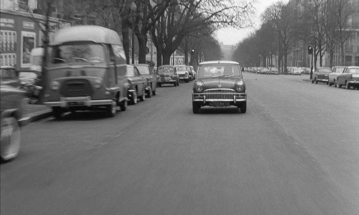 La Peau Douce (The Soft Skin) (1964) movie still: wide — A wide city street lined with parked vintage European cars and bare trees. The road…