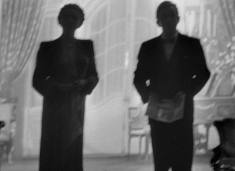 Notorious (1946) movie still: fullbody — An opulent room with tall arched windows features two silhouetted figures standing centrally. The man and…