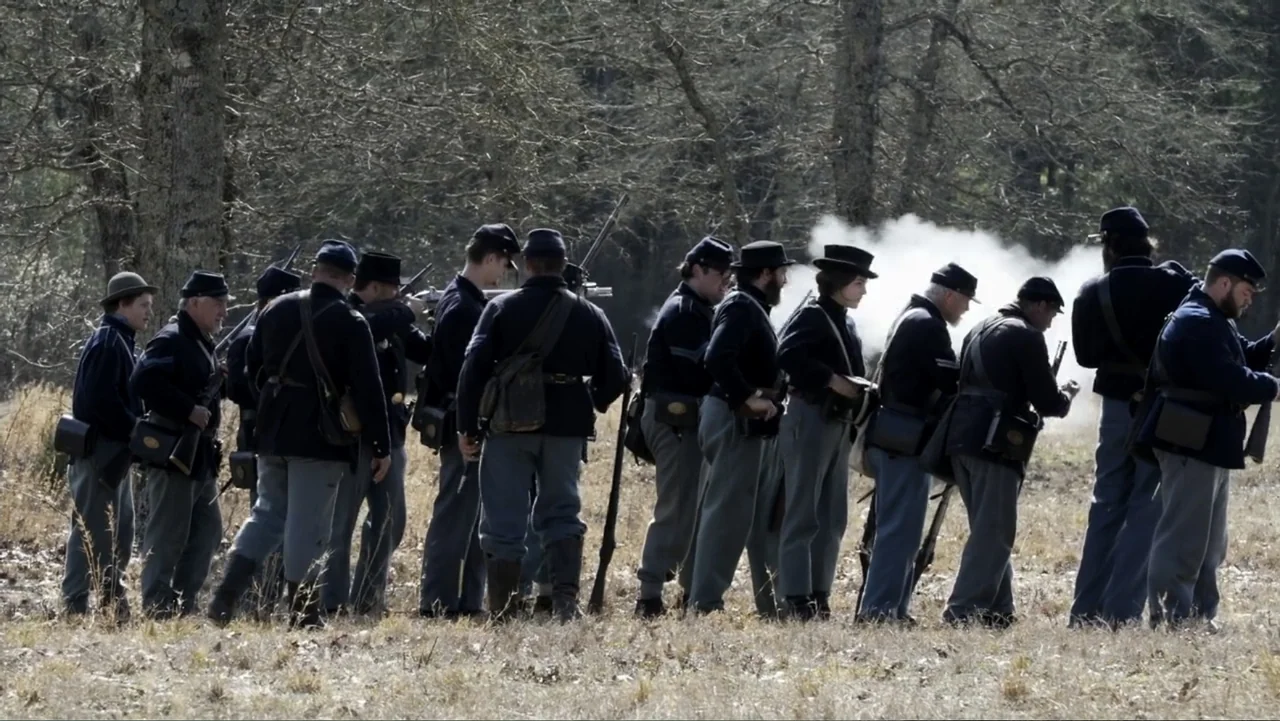 Kill Cavalry (2021) movie still: fullbody — A group of Union soldiers in period uniforms stand in a field with bare trees. The men hold muskets and…