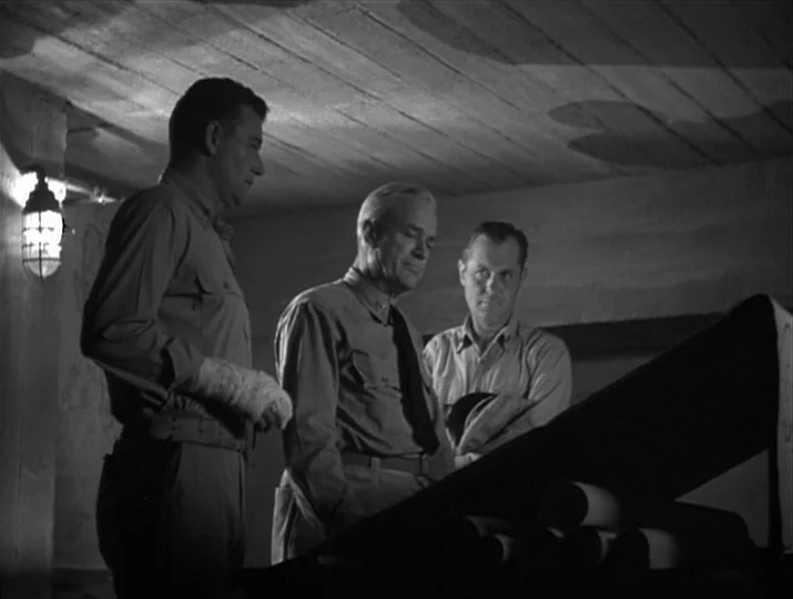 They Were Expendable (1945) movie still: medium — A concrete bunker room with plank-formed ceiling textures and a caged wall lantern. Three men in…
