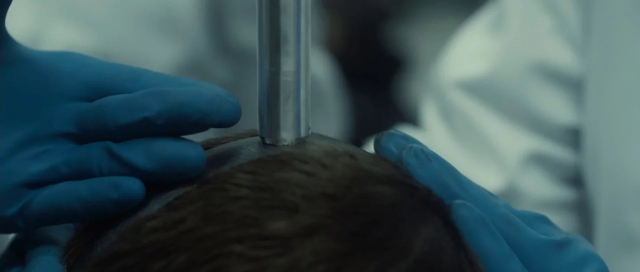 Universal Soldier: Regeneration (2009) movie still: closeup — A close-up view of a metal device contacting the top of a human head. Blue…