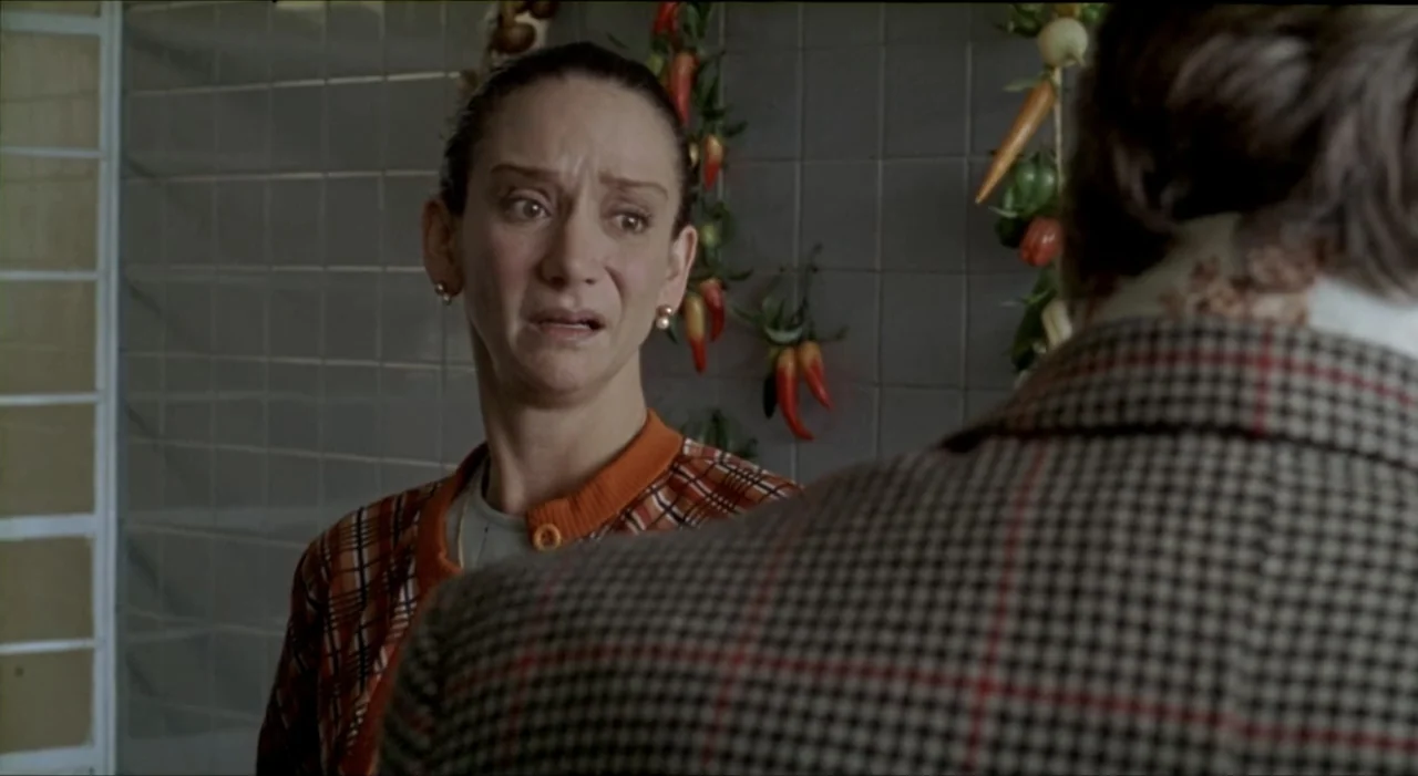 Sex, Love And Other Perversions II (2006) movie still: medium — A tiled room with vegetables hanging on the wall behind the main subject. A woman…