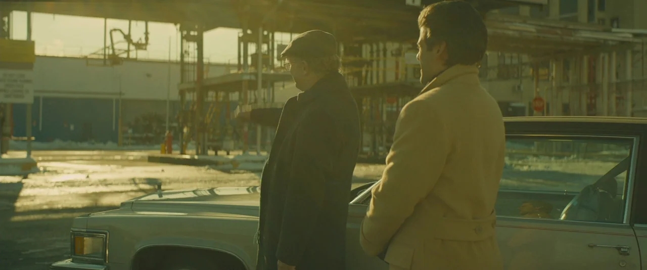 A Most Violent Year (2014) movie still: medium — An industrial paved lot stretches out with metal structures visible in the hazy distance. Two men…