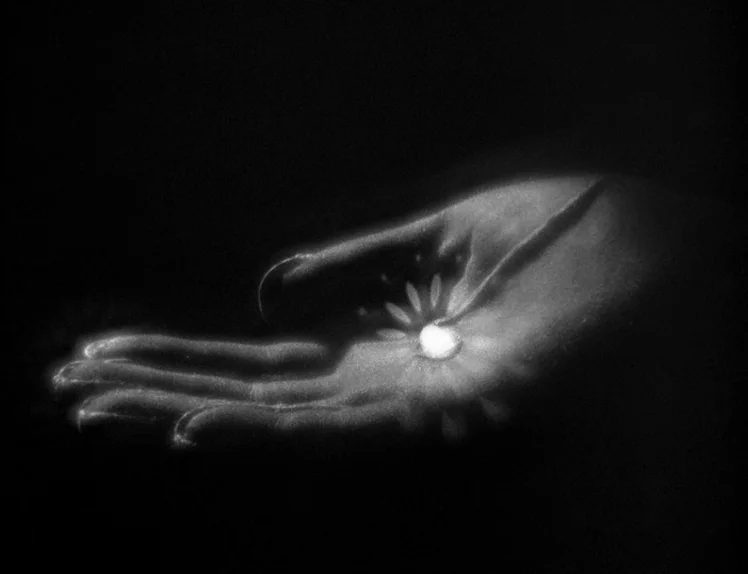 Prison (1949) movie still: closeup — An abstract dark space features a disembodied human hand floating against a black void. A luminous circular…