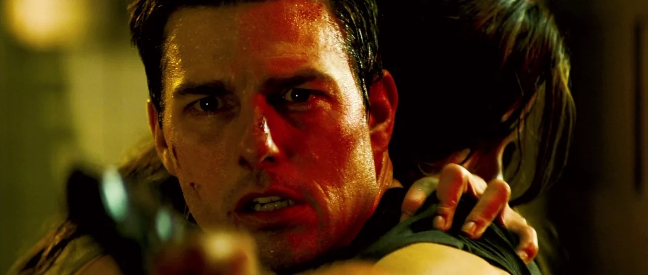 Mission: Impossible III (2006) movie still: closeup — An interior space with low lighting obscured by extreme contrast and shadow. A man holding a…