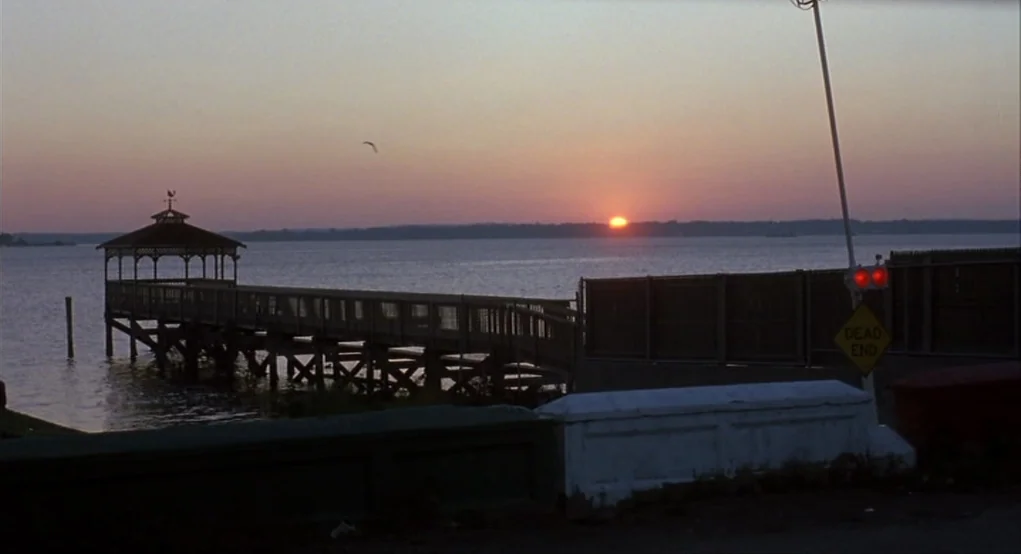 Summer of Sam (1999) movie still: establishing — A wooden pier with a gazebo extends into a calm body of water at dusk. A road-side dead end sign…