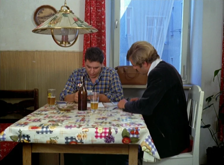 The Merchant Of The Four Seasons (1971) movie still: medium — A small room features a wooden table covered by a patterned fruit-themed tablecloth.…