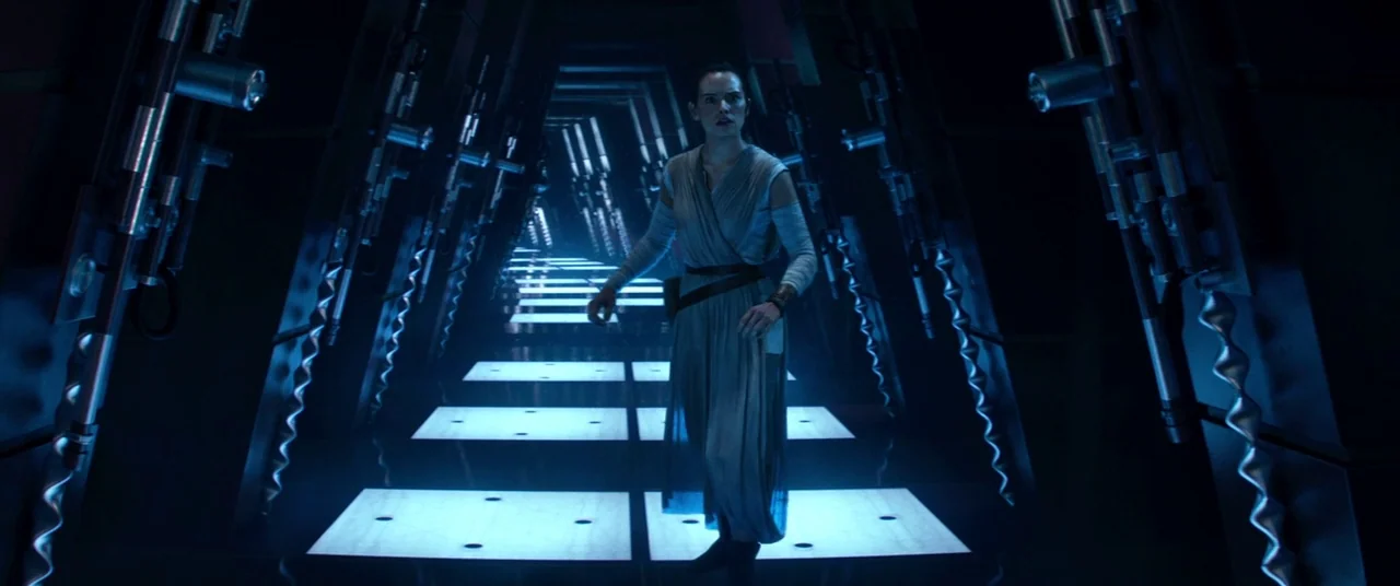 Star Wars: The Force Awakens (2015) movie still: fullbody — A dark, narrow metallic corridor features illuminated square tiles recessed into the…