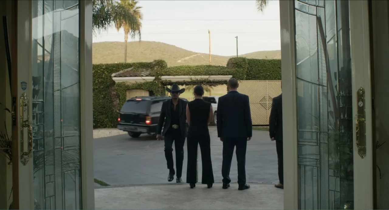 Instantes Capturados (2022) movie still: fullbody — A group of four people approach a large house from a paved outdoor driveway. The subjects move…