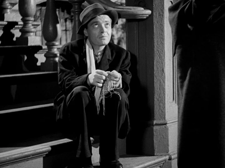 Stranger on the Third Floor (1940) movie still: medium — A man sits on a stone staircase at night near a decorative balustrade. The man crouches on…