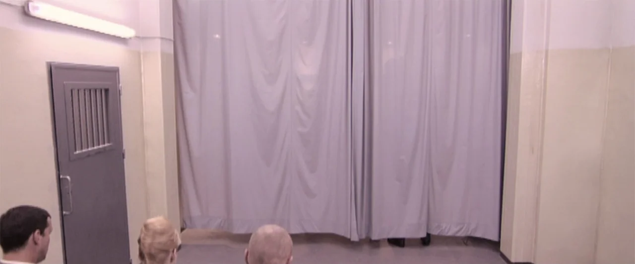 Dancer in the Dark (2000) movie still: medium — A sterile corridor features light-colored walls and a metal door with a small window. Three people…