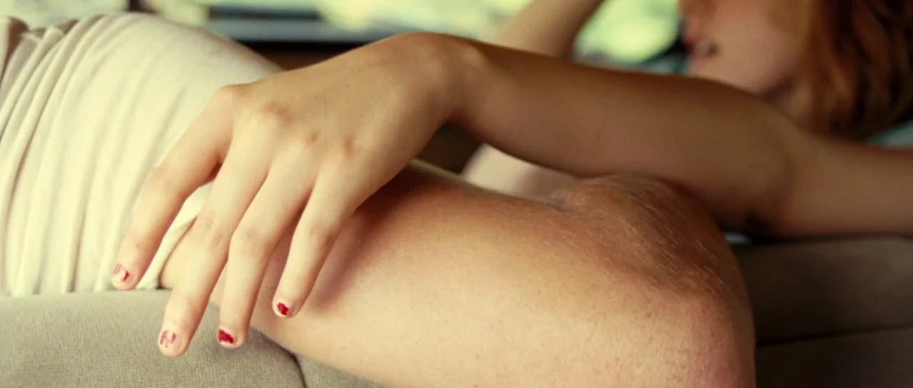 On The Road (2012) movie still: closeup — A close-up view shows a hand resting across an arm on a sofa. The person's fingers feature red nail polish…