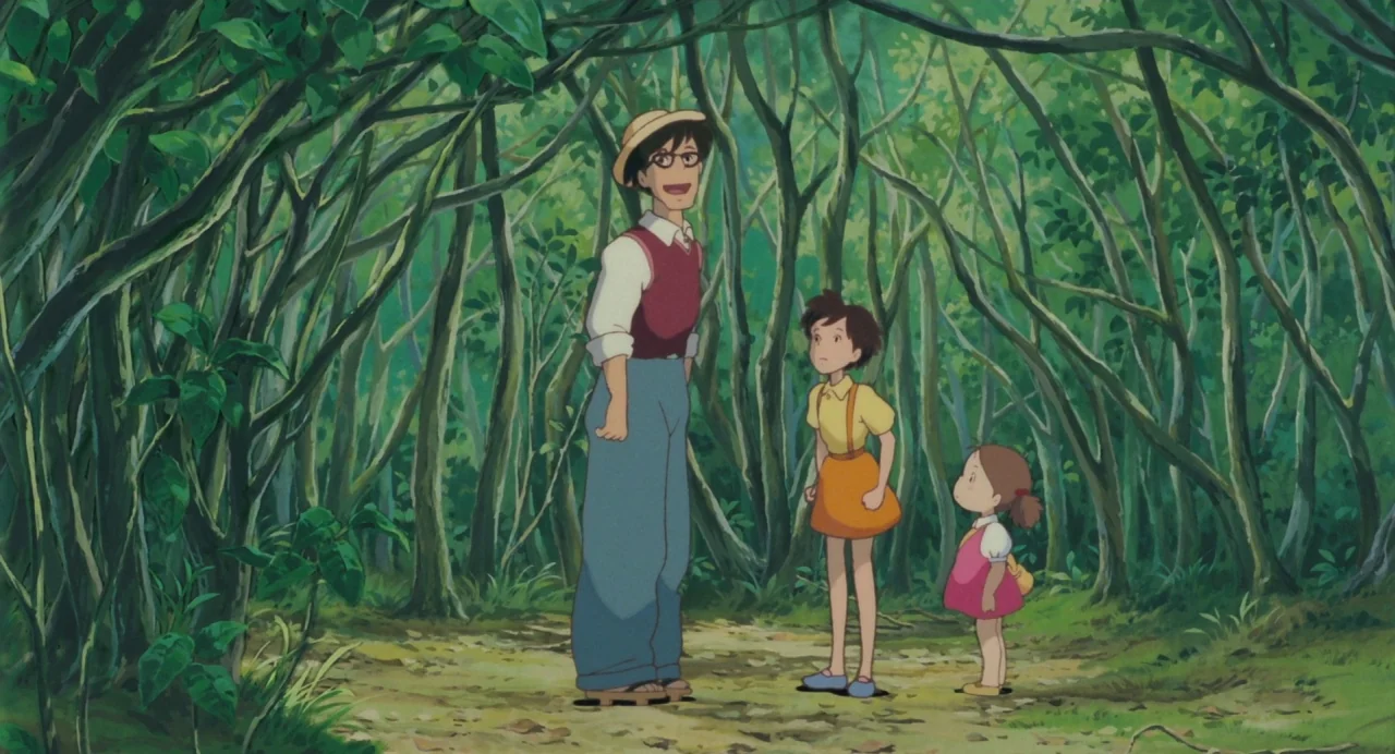 My Neighbour Totoro (1988) movie still: fullbody — A dense green woodland path with thin trees framing a small clearing. A man in a straw hat stands…