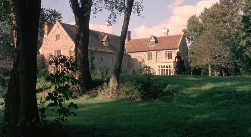Witchfinder General (1968) movie still: wide — A large stone manor house with multiple gables sits on a grassy hill. A woman in a dark dress stands…