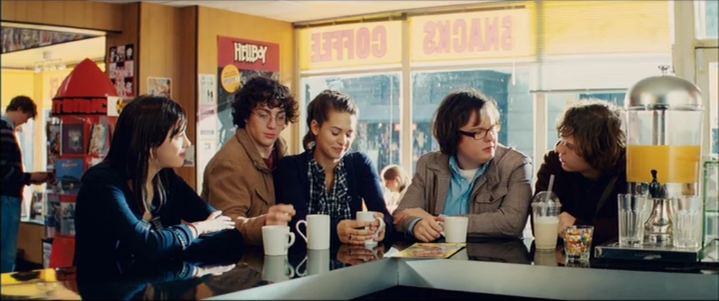 Kick Ass (2010) movie still: wide — A group of five teenagers sit at a counter inside a brightly lit diner. They converse over coffee and drinks…