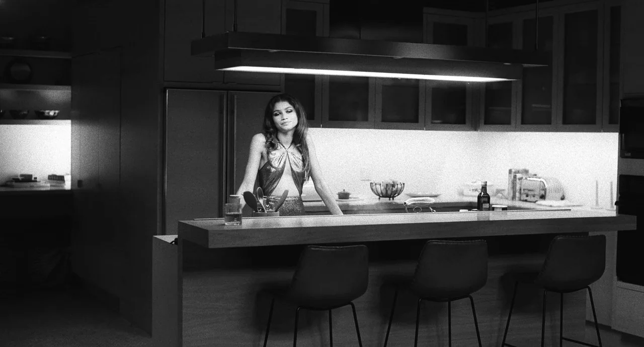 Malcolm & Marie (2021) movie still: medium — A modern kitchen features dark cabinetry, stainless steel appliances, and a minimalist bar counter. A…