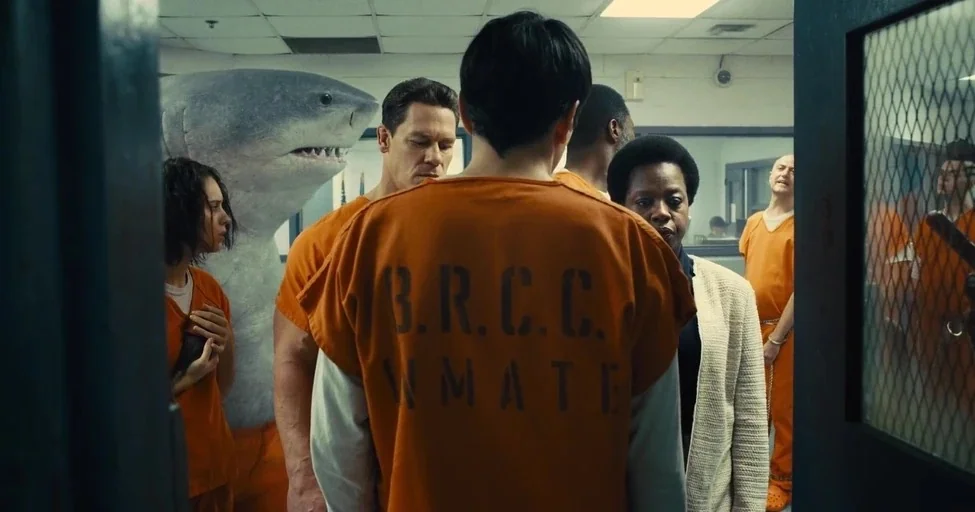 The Suicide Squad (2021) movie still: medium — A utilitarian holding area with light-colored tile walls and a drop ceiling. Several individuals in…