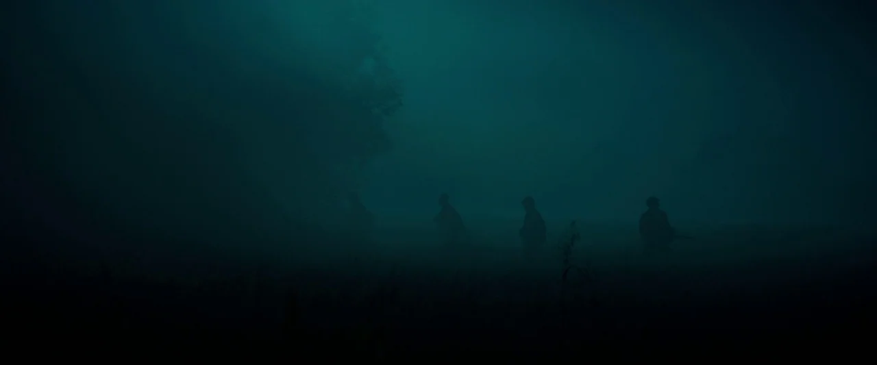 Overlord (2018) movie still: wide — A dark field is engulfed in thick, impenetrable teal-colored night fog. Four human silhouettes move slowly…