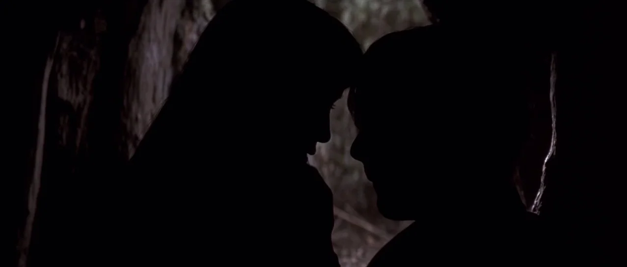 Snow Falling on Cedars (1999) movie still: medium — Two people stand in the dark entrance of a rocky cave. They face each other with foreheads…
