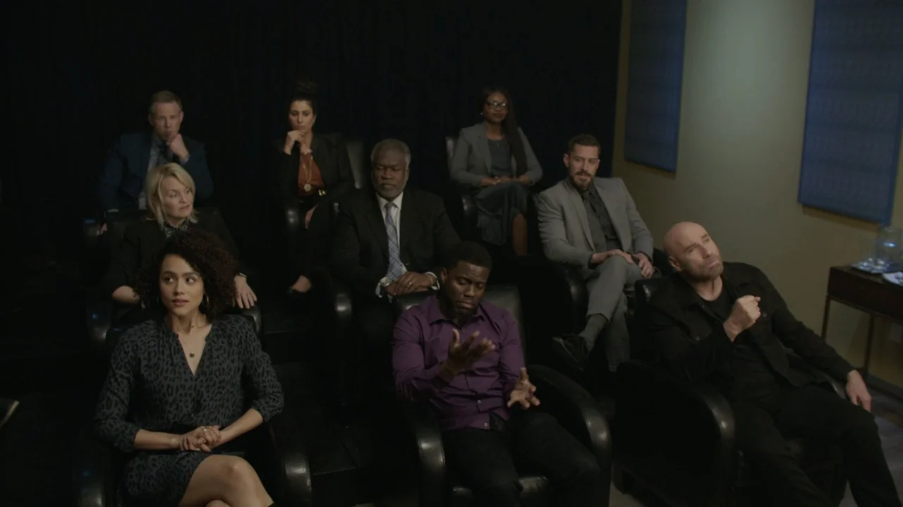 Die Hart (2023) movie still: medium — A dark, dimly lit screening room contains rows of black leather armchairs for spectators. Nine diverse people…