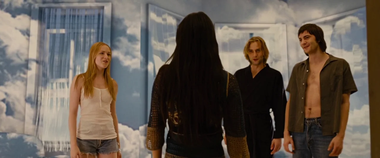 Across the Universe (2007) movie still: medium — An interior space features walls covered in a surreal sky and cloud-patterned mural. Four people…