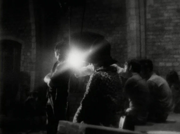 Cuadecuc, Vampir (1971) movie still: medium — A dark, brick-lined cellar space serves as the setting for a gathering of people. A blindingly bright…