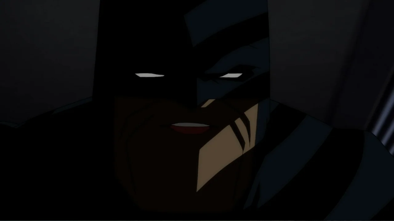 Batman: The Dark Knight Returns, Part 1 (2012) movie still: closeup — A dark, dimly lit environment obscures the surroundings. The masked figure…