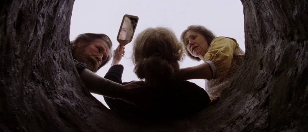 Cold Mountain (2003) movie still: wide — Three people peer down into a circular stone opening against a pale overcast sky. The individuals lean over…