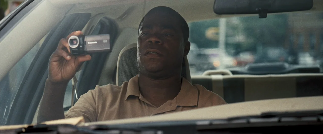 Cop Out (2010) movie still: medium — The interior of a car features a light-colored headrest and dashboard dashboard details. A man sits in the…