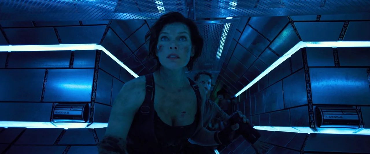Resident Evil: The Final Chapter (2016) movie still: medium — A dark, narrow metallic passageway features industrial wall panels with illuminated…